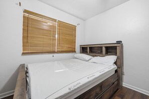 A single bed with a wooden headboard, white bedding, and a window with blinds. - Attention football fans!  Charming 3-bedroom townhome close to UF. Small pet ok (Gainesville)