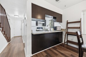 A modern kitchen with a dark backsplash, stainless steel appliances, and a granite countertop. - Attention football fans!  Charming 3-bedroom townhome close to UF. Small pet ok (Gainesville)