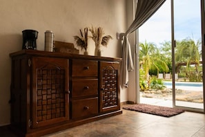 A wooden cabinet with drawers and a decorative panel, a coffee maker, a thermos, and dried plants on top. - Casa Corazon Zen-Double Suite (Petatlán)