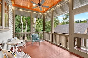 A covered porch with a ceiling fan, wooden deck, and a view of trees. - Day's End Retreat | Pets, Game Room, Fire Pit & Views in Cheshire Village! (Black Mountain)