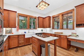 A modern kitchen with wooden cabinets, a central island, and a large window. - Day's End Retreat | Pets, Game Room, Fire Pit & Views in Cheshire Village! (Black Mountain)