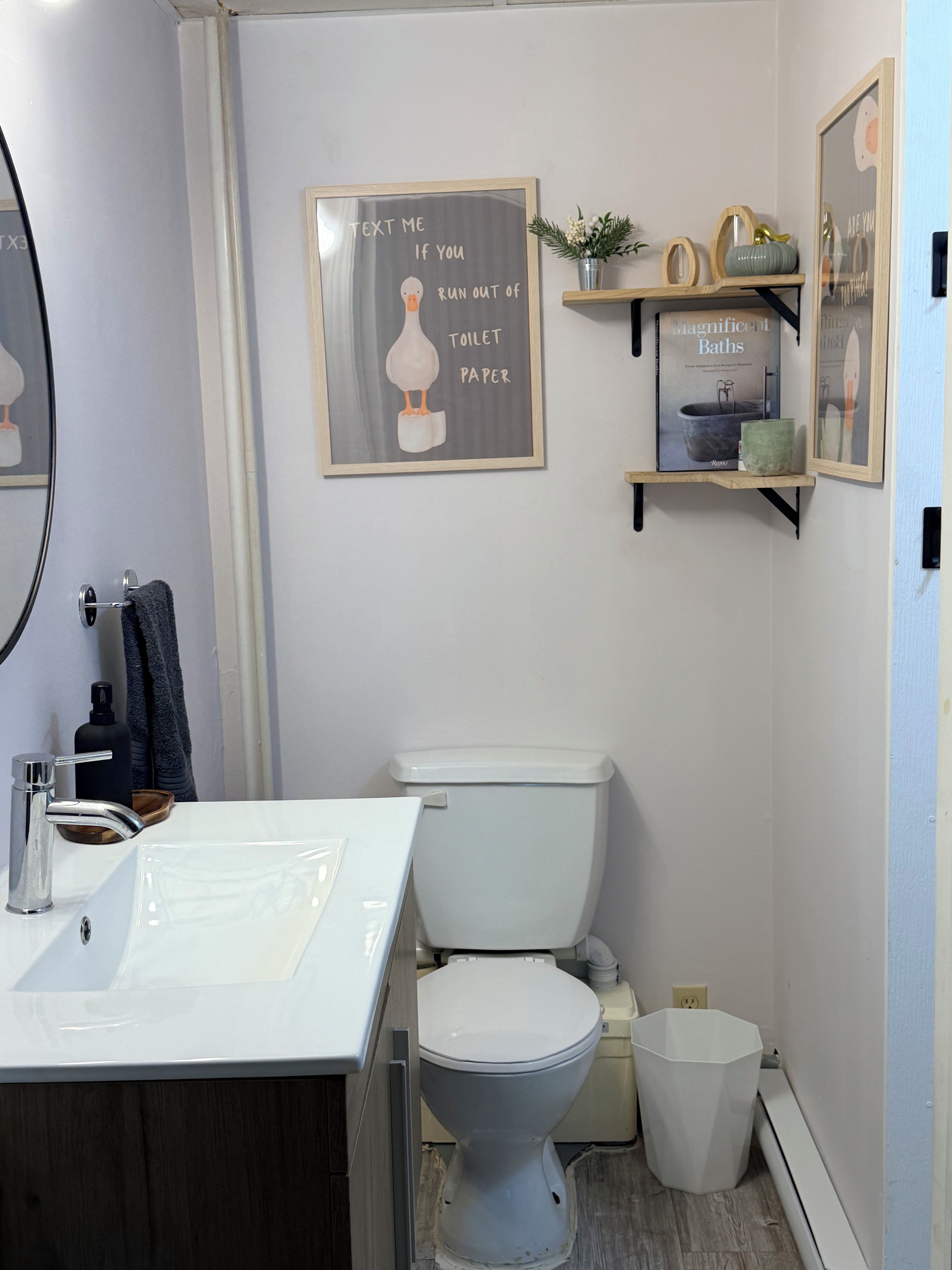 A bathroom with a white toilet, a sink with a mirror, and a framed sign on the wall.