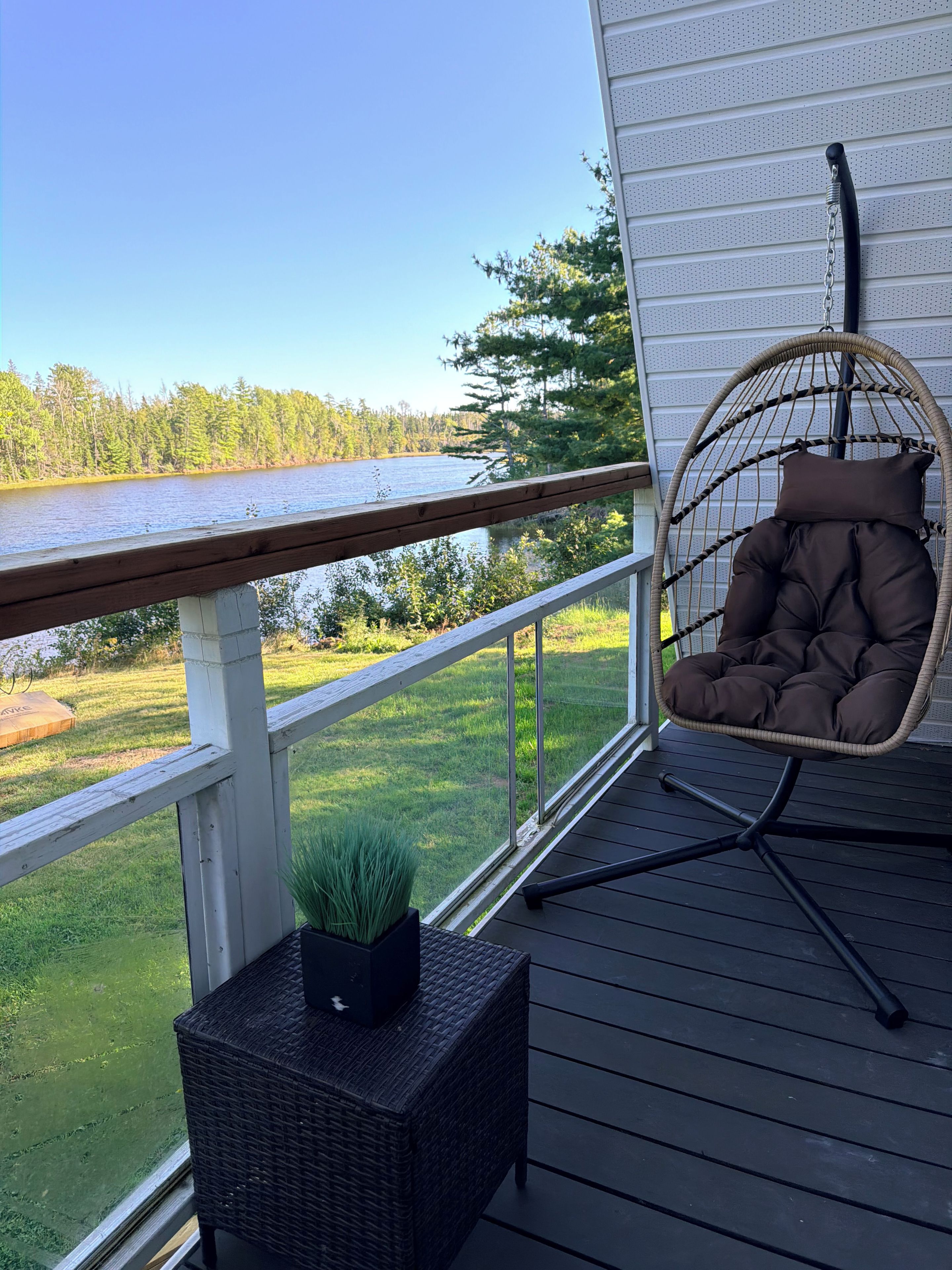 Una terraza de madera con una silla de mimbre y una pequeña planta en maceta.