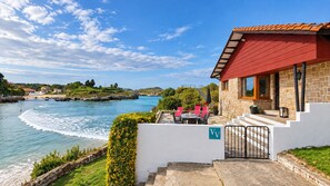 A coastal property with a stone building, a balcony with red chairs, and a view of the sea. - House in Llanes | Directly on the beach | Rebellín (Celorio (Llanes))