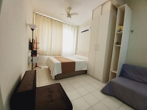 A compact room with a bed, a sofa, a desk, and a wardrobe. - Cozy in the heart of Leme (Rio de Janeiro)
