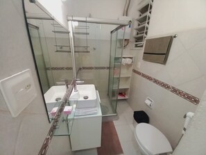 A bathroom with a glass shower enclosure, a white sink, and a toilet. - Cozy in the heart of Leme (Rio de Janeiro)