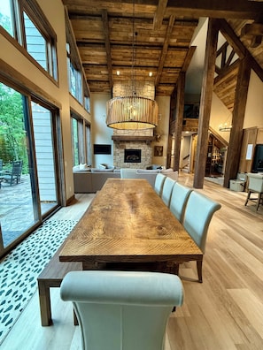 Un vaste espace dédié à la salle à manger, avec une grande table en bois et des bancs recouverts d’un tissu bleu clair.