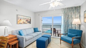 A room with a sofa, a chair, a table, and a balcony with a view of the ocean. - Ocean front condo in beautiful Ormond Beach at Tropic Sun Towers (Ormond Beach)