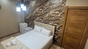 Une chambre à coucher avec un lit, une table de chevet, une porte en bois et un mur décoré d’un motif marbré.