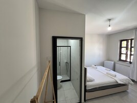 Un dormitorio con cama, ventana, radiador y espejo.