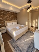 Un dormitorio moderno con una cama grande, una mesita de noche, un aparador y una alfombra estampada.