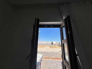 An open door leading to a balcony with a clear view of a residential area and a building in the distance. - Golden Sur Butik Otel (Diyarbakir)