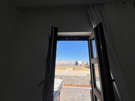 Puerta abierta que da a un balcón con vistas despejadas a una zona residencial y un edificio a lo lejos.