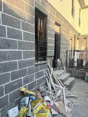 A construction site with a partially constructed brick wall, a window with metal bars, and various construction materials scattered around. - Golden Sur Butik Otel (Diyarbakir)