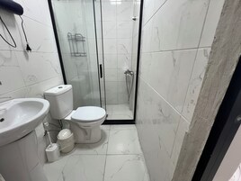 Un baño con inodoro, lavabo y ducha.
