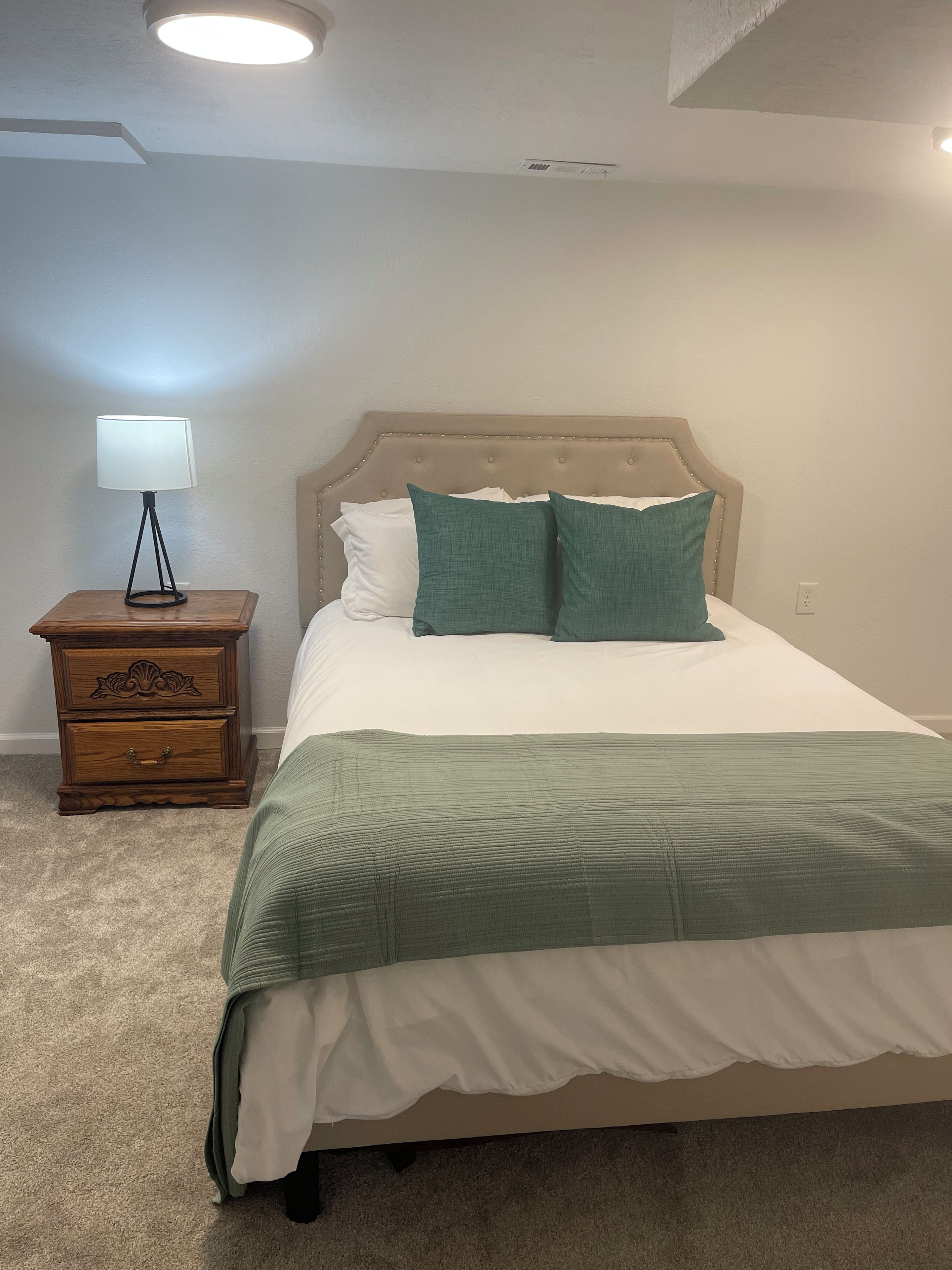 A bedroom with a bed, a nightstand, a lamp, and a ceiling light.