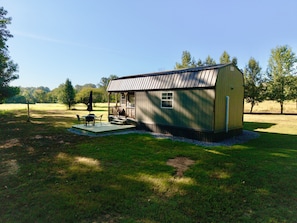 A small wooden cabin with a porch, a table, and chairs. - Serene 1-bedroom tiny house in charming Strawberry, steps away from the creek (Strawberry)