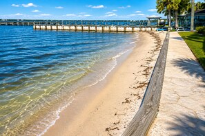 A beach with a wooden walkway, clear blue water, and a distant pier. - Bayfront Retreat for Two - Pool + Gulf Nearby (Fort Walton Beach)