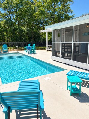 A swimming pool with blue chairs and a covered seating area. - Peaceful 3-bedroom house with a Heated Pool! (Oak Island)
