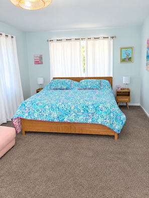 A bedroom with a bed, two bedside tables, a nightstand, a window with curtains, and a wall with a picture. - Peaceful 3-bedroom house with a Heated Pool! (Oak Island)