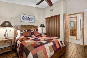 A bedroom with a wooden bed, two bedside lamps, a ceiling fan, and a large window with curtains. - The Hilltop Lookout | Catalina Mountain Views (Tucson)