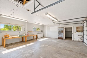 A spacious room with a high ceiling, large windows, and a view of greenery outside.