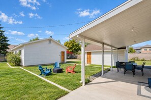 A covered patio area with outdoor seating, a small shed, and a well-maintained lawn.