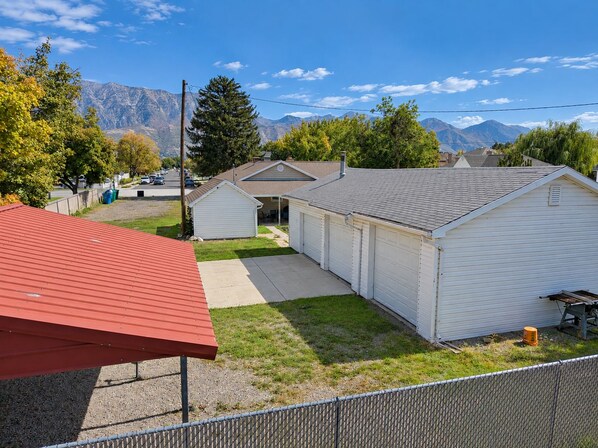 A residential area with a red-roofed structure, a white garage, and a mountain backdrop.