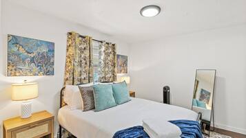 Una habitación de hotel con cama, lámparas de noche, un espejo y obras de arte en las paredes.
