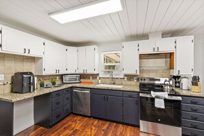 A modern kitchen with white cabinets, a built-in oven, a dishwasher, and a granite countertop.