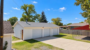 A single-story building with a garage, a paved driveway, and a fenced yard.