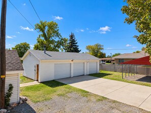 A single-story building with a garage, a paved driveway, and a fenced yard.