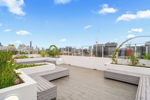A rooftop terrace with a city view, wooden flooring, and planters with greenery. - Funky Teneriffe - 2Bed-2Bath-Balcony-1Car (Teneriffe)