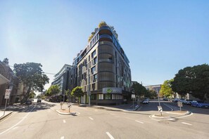 Ein modernes Gebäude mit einer gewölbten Fassade, einem gut erkennbaren Eingang und einem Schild, das einen Parkbereich für Pkw anzeigt.