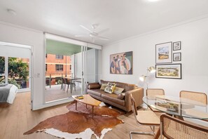 A modern living room with a leather sofa, glass coffee table, and a cowhide rug. - Funky Teneriffe - 2Bed-2Bath-Balcony-1Car (Teneriffe)