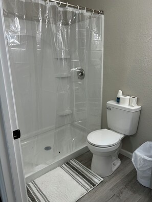 A bathroom with a shower enclosure, toilet, and a small trash bin. - Newly Renovated Tallahassee Retreat Minutes from FAMU, FSU & Downtown (Tallahassee)