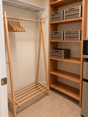 A walk-in closet with a wooden clothes rack, open shelving, and a metal-framed storage unit. - Redford Casita, 1BD/1BA, Across from Empire Polo, King Bed (Indio)