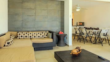 Een woonkamer met een modulaire bank, een klein tafeltje met een mand, en een eethoek met stoelen en een tafel.