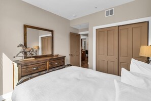 Ein Schlafzimmer mit Bett, Kommode, Spiegel und Kleiderschrank.