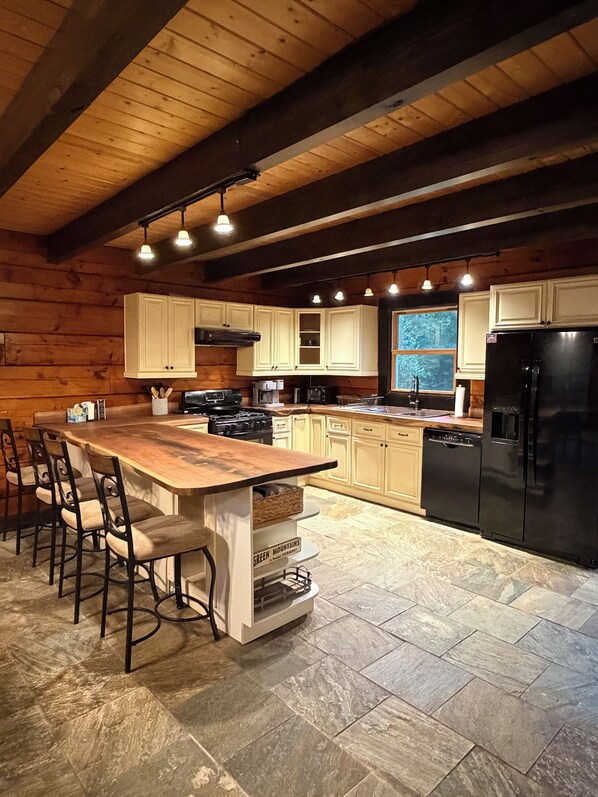 Una cocina con una isla grande, armarios de madera y suelo de baldosas de piedra.