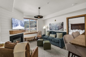 A living room with a fireplace, a television, a sofa, and a dining area. - Silverado 310 | Canyons Village | Pool, Hot Tub & Walk to Ski (Park City)