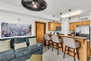 Une cuisine moderne avec des meubles en bois, un coin bar et un grand tableau accroché au mur.