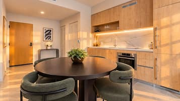 A modern kitchen with wooden cabinets, a round dining table with four chairs, and a built-in oven.