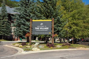 Willkommensschild für The Village at Whitefish Mountain Resort, das Einrichtungen wie Unterkünfte, Check-in, Einkaufsmöglichkeiten, Gastronomie, Verleih und mehr anzeigt.