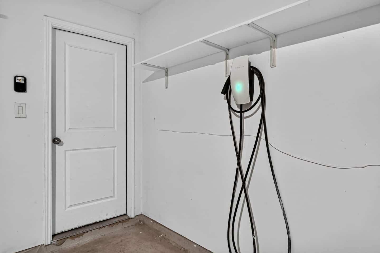 Une porte blanche avec une serrure et un petit panneau de commande fixé au mur, sur le côté gauche.