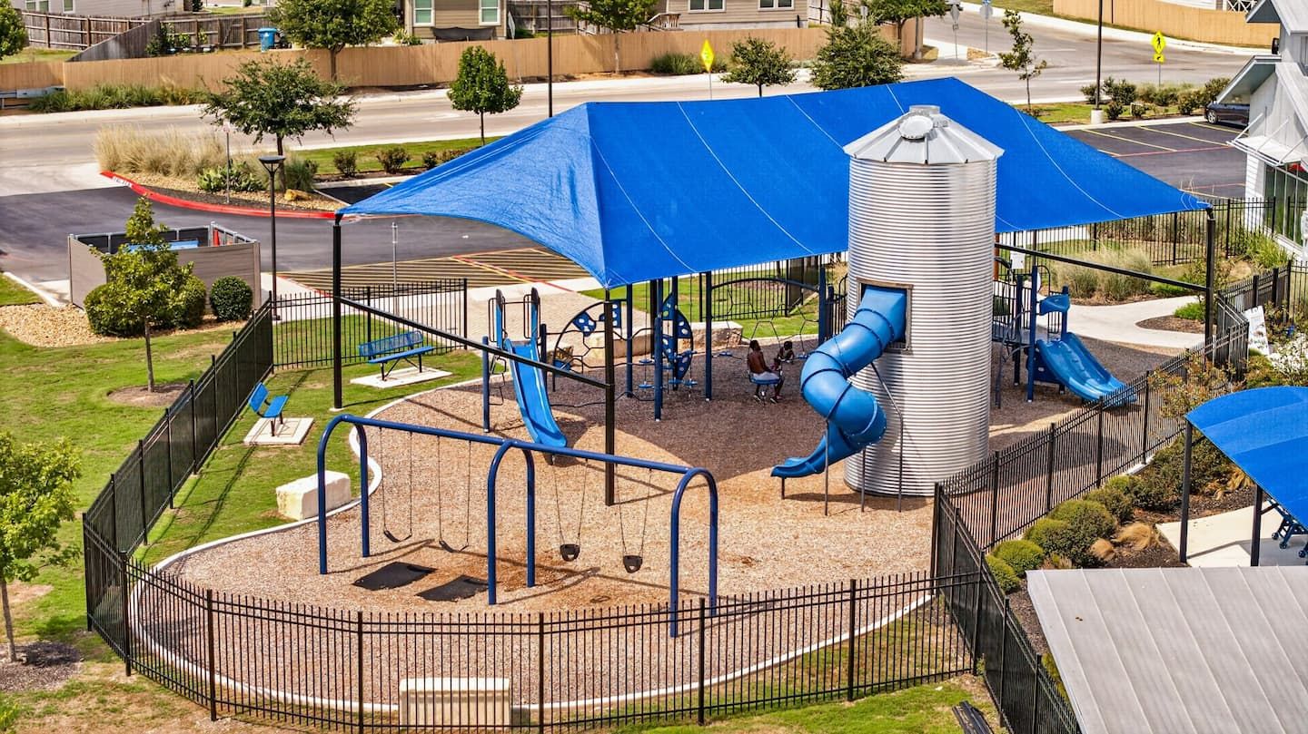 Une aire de jeux avec un toboggan, des balançoires et une structure d’escalade.