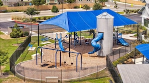 Une aire de jeux avec un toboggan, des balançoires et une structure d’escalade.