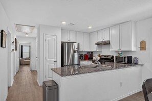 A modern kitchen with white cabinetry, stainless steel appliances, and a granite countertop.