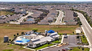 Un quartier résidentiel avec des maisons, une piscine et un bâtiment doté d’un toit bleu.