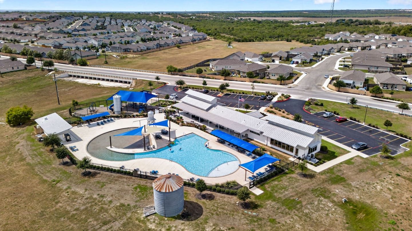 Vue aérienne d’un quartier résidentiel avec une piscine, un parking et des maisons.
